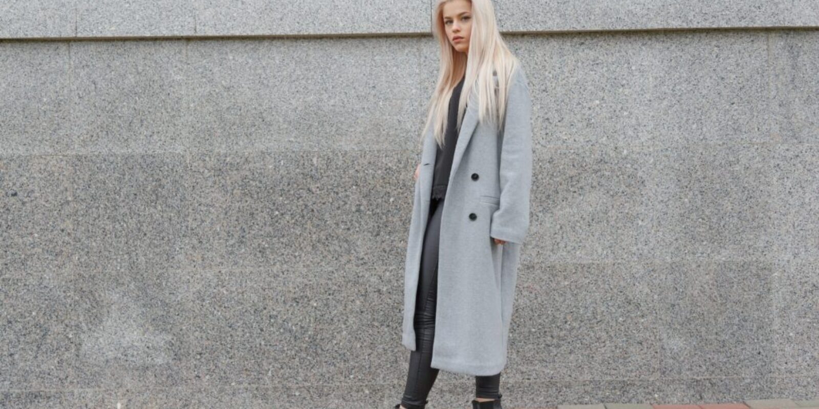 Fashion style young elegant woman in gray fur coat walking at city street.
